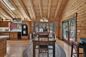 A wooden interior with a dining area, kitchen, and large windows. - Peaceful Log Cabin Getaway on 6 Private Acres (Grass Valley)