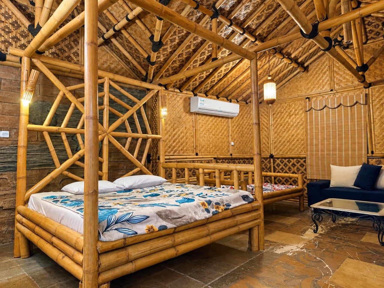 Ein Zimmer mit einem Bambus-Himmelbett, einer Couch und einer Klimaanlage.