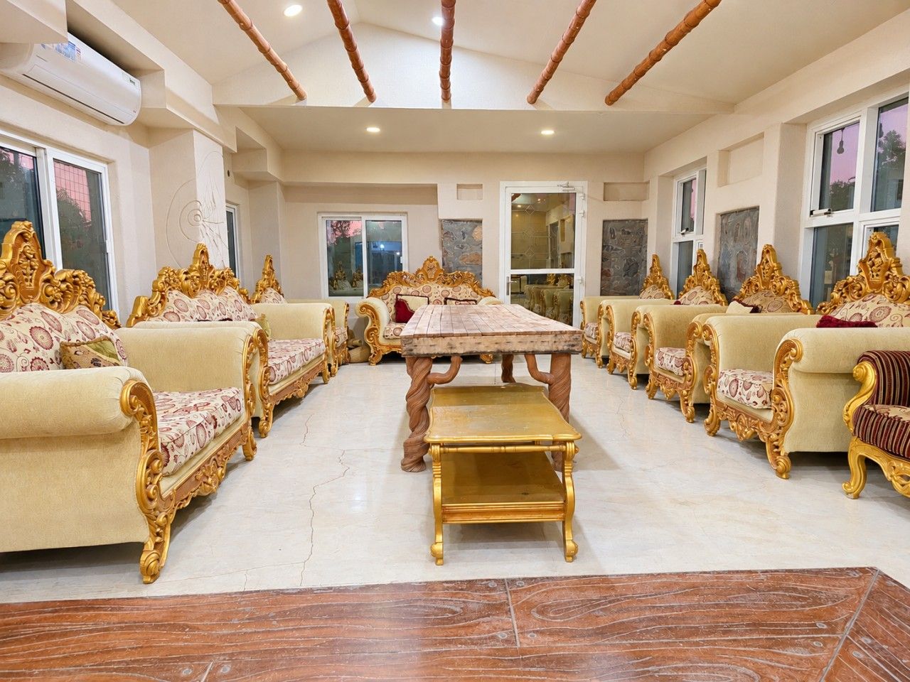 A formal dining room with ornate golden furniture, a central table, and a marble floor.