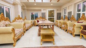 A formal dining room with ornate golden furniture, a central table, and a marble floor.