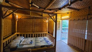 Ein Zimmer mit einem Bett, Bambuswänden und einem Balkon mit Blick.