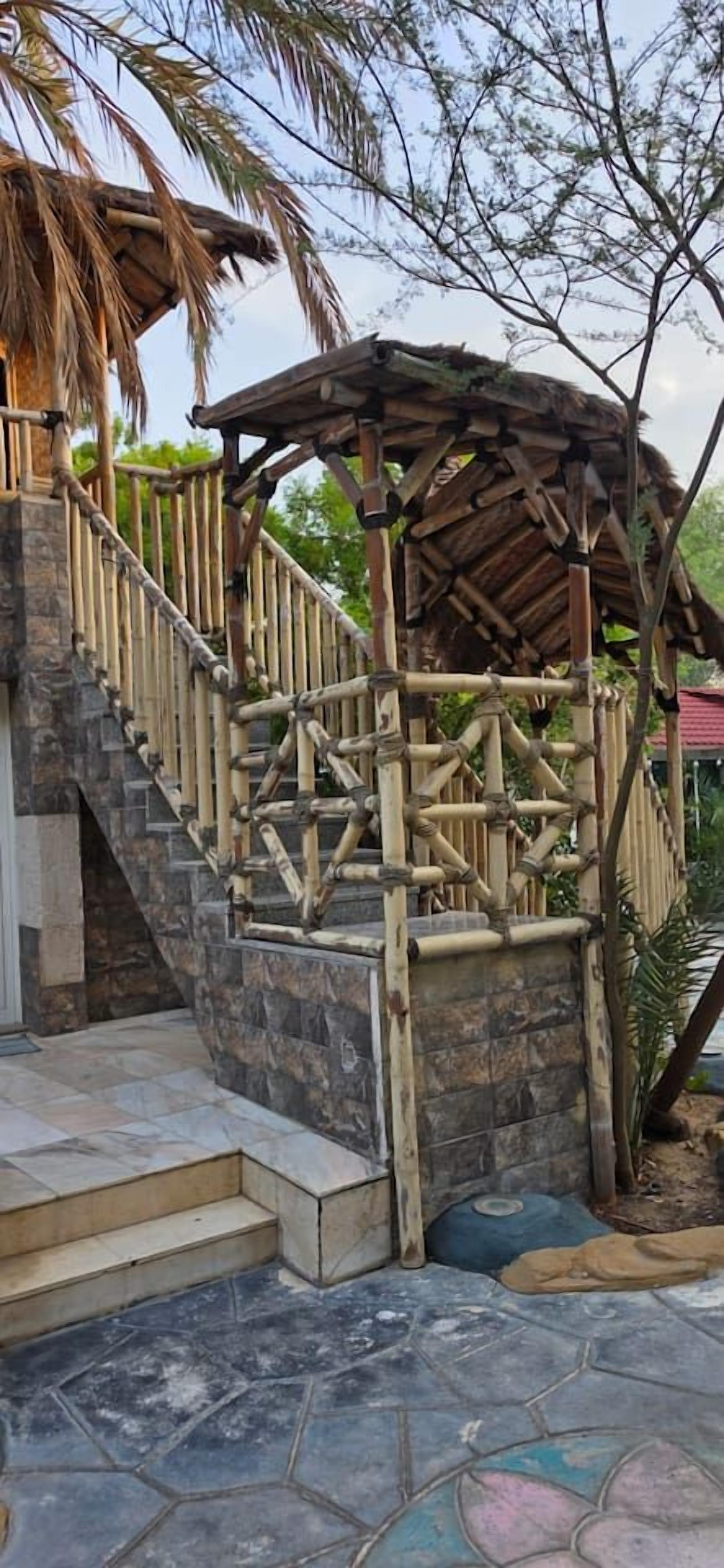 A stone staircase leading to a wooden gazebo with a thatched roof.