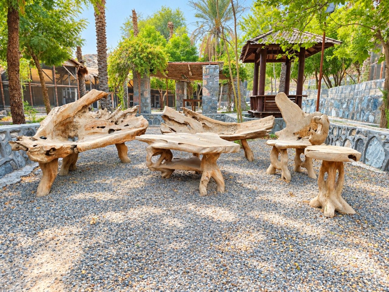 Outdoor seating made of natural wood, surrounded by pebbles and trees.