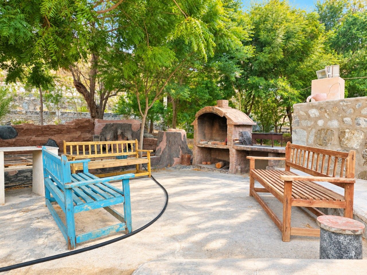Un espace extérieur aménagé avec des bancs et un four en pierre.