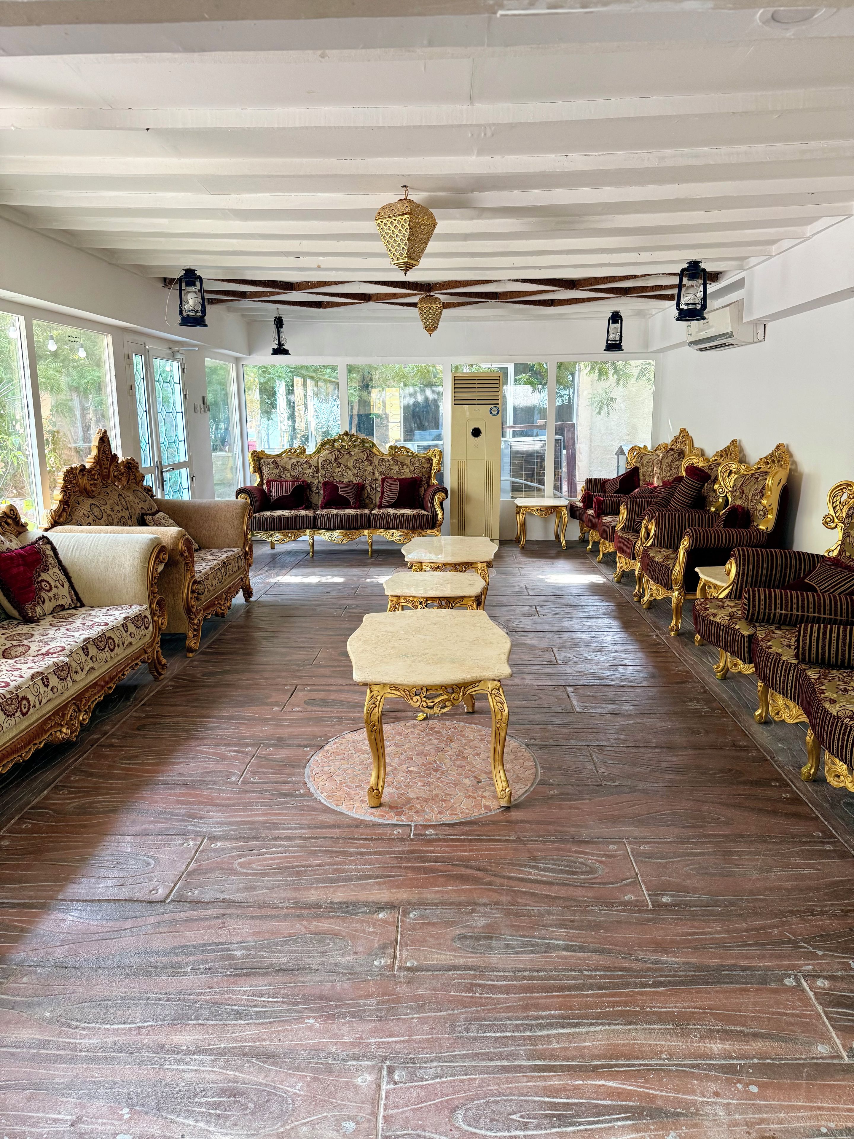 A spacious room with ornate golden furniture, large windows, and a tiled floor.