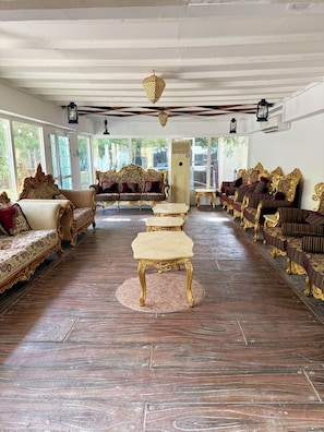 A spacious room with ornate golden furniture, large windows, and a tiled floor.