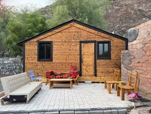 A wooden cabin with a stone wall, a sofa, a bench, and two chairs.