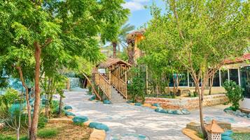 A pathway leading to a wooden staircase surrounded by lush greenery and a stone wall.