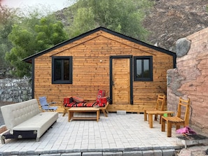 A wooden cabin with a sofa, chairs, and a small table outside.