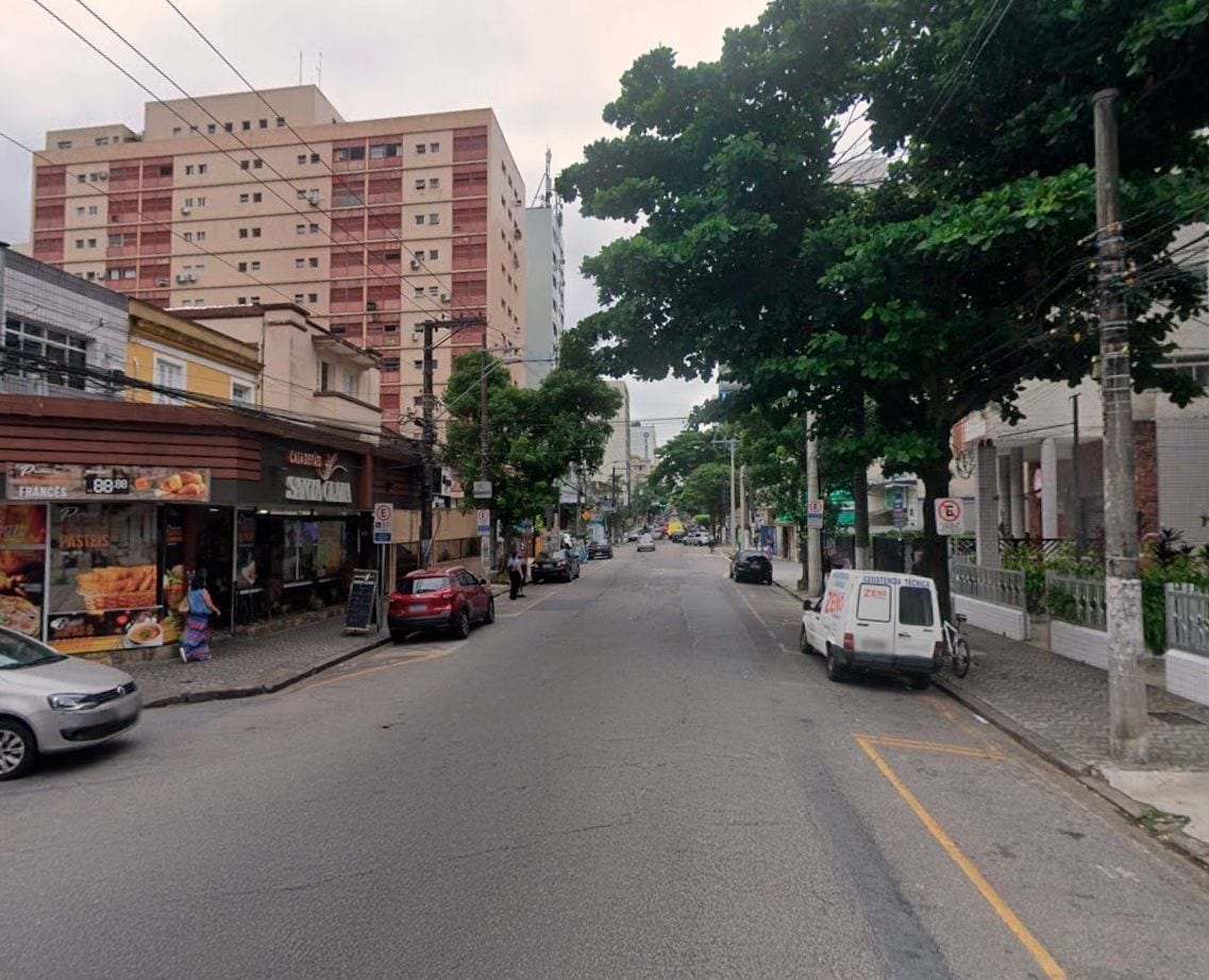 A street with buildings, parked cars, and a van.