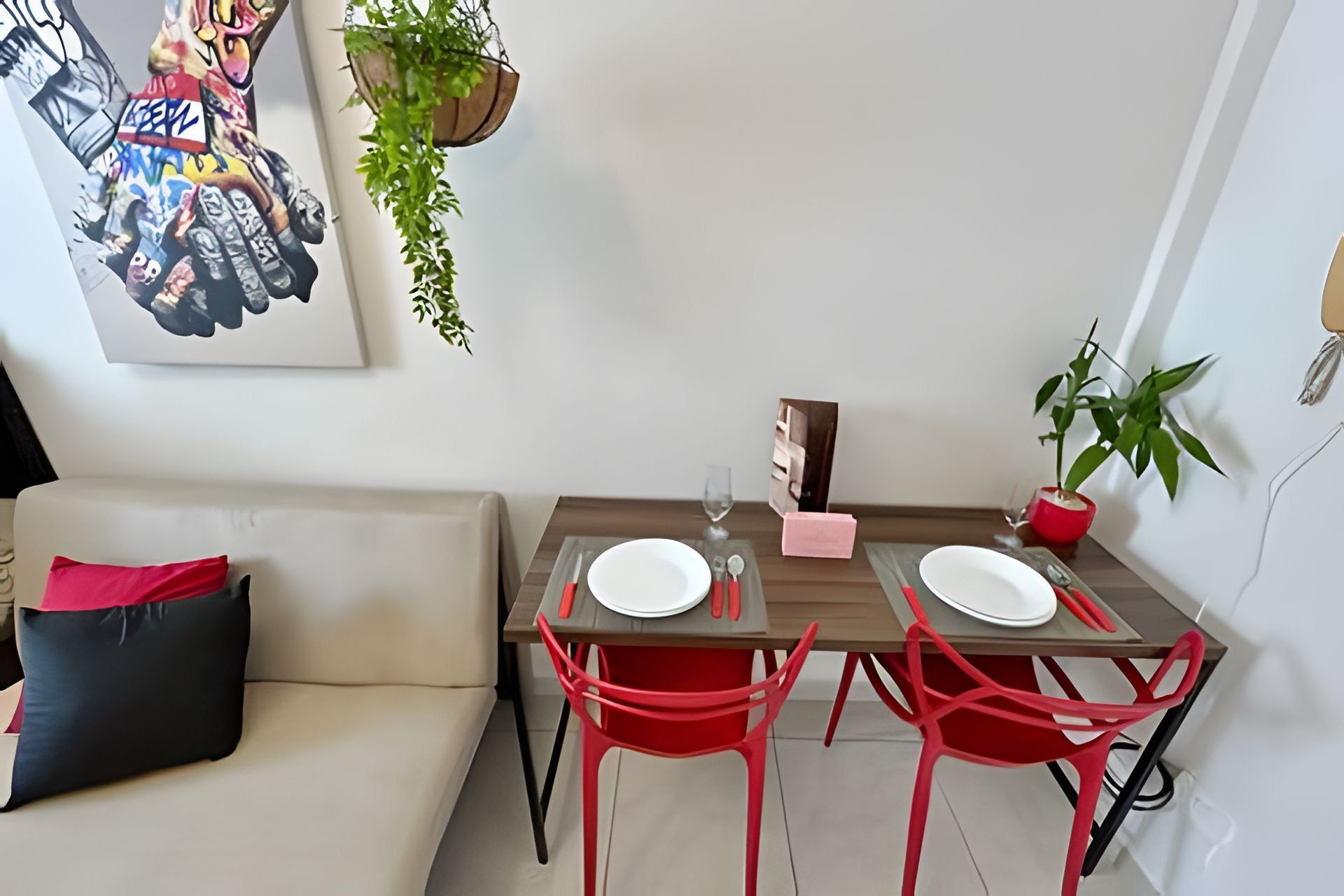 A dining area with two red chairs, a wooden table, and a white plate on each chair.