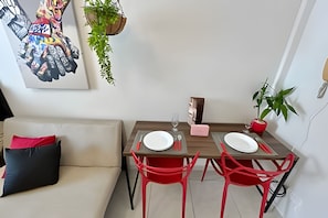 Un coin repas avec deux chaises rouges, une table en bois et une assiette blanche sur chaque chaise.