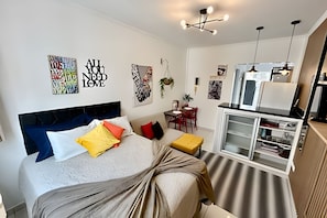 A modern bedroom with a bed, bedside tables, a desk, and a kitchenette. - SHB - Studio no Gonzaga à Beira Mar (Santos)