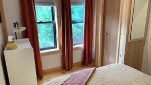 Una camera da letto con due finestre, un letto, un comodino e una porta.