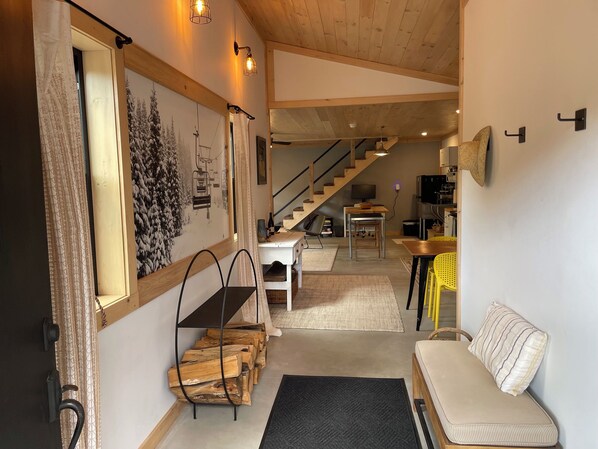 A cozy interior with a staircase, a dining area, and a living space with a sofa and a bench.