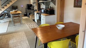 Una cucina moderna con un tavolo di legno, sedie gialle e un'area pranzo con un tappeto.