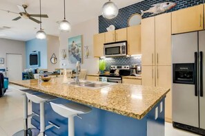 A modern kitchen with granite countertops, stainless steel appliances, and a bar area with stools. - Isla Bella - 2BR Beach Condo with Pools & Hot Tubs (South Padre Island)