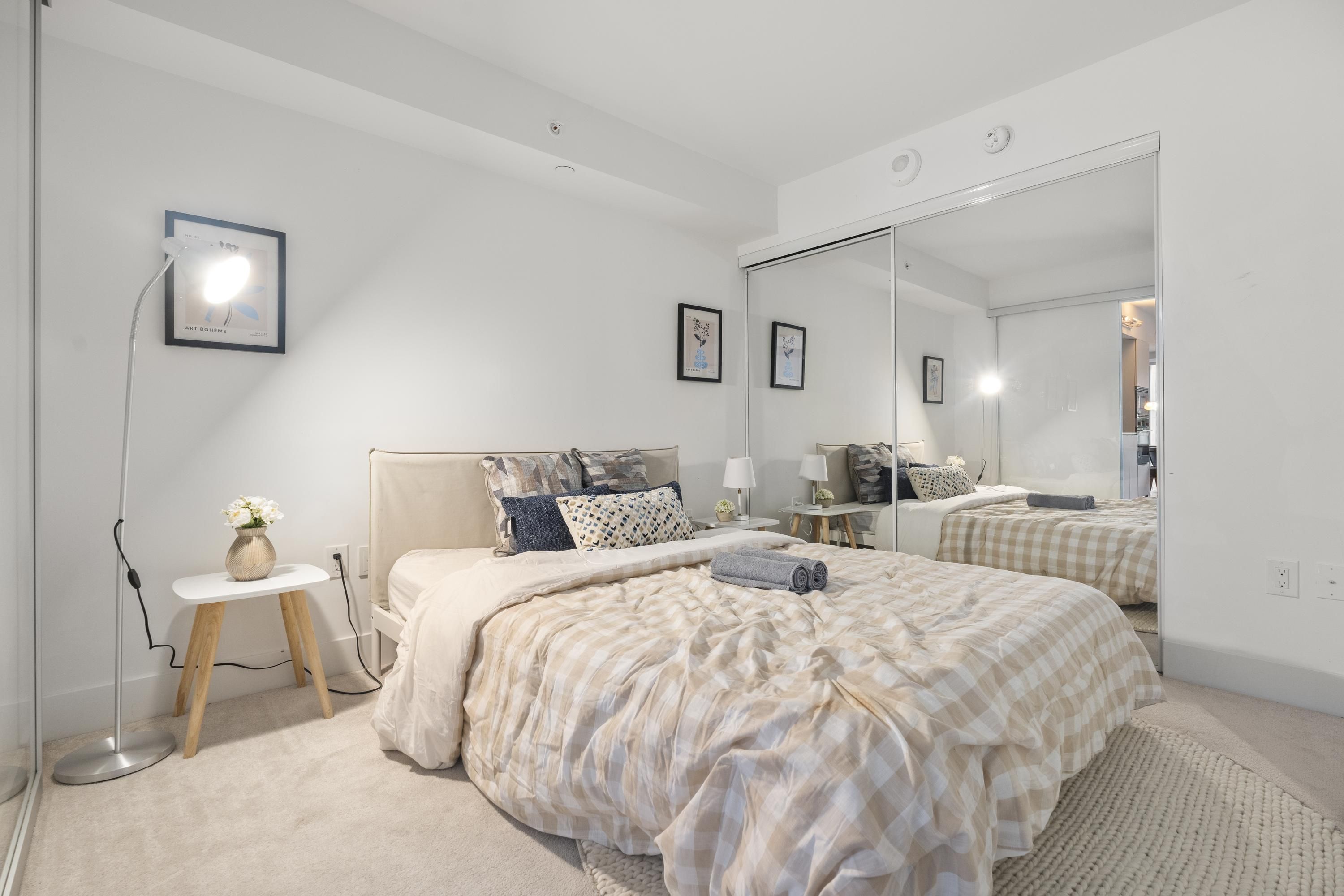 Une chambre à coucher avec un grand lit, des tables de chevet, un miroir et une lampe sur pied.