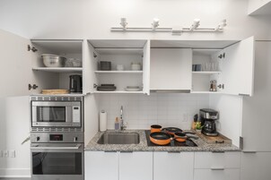 Een moderne keuken met witte kasten, een inbouwoven, een magnetron en een koffiezetapparaat.