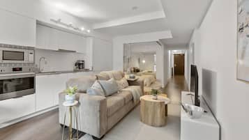 A modern living space with a kitchen, sofa, coffee table, and TV.