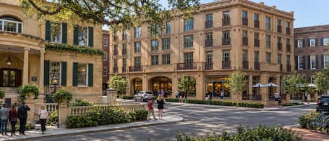 A multi-story building with a brick facade, large windows, and outdoor seating areas.
