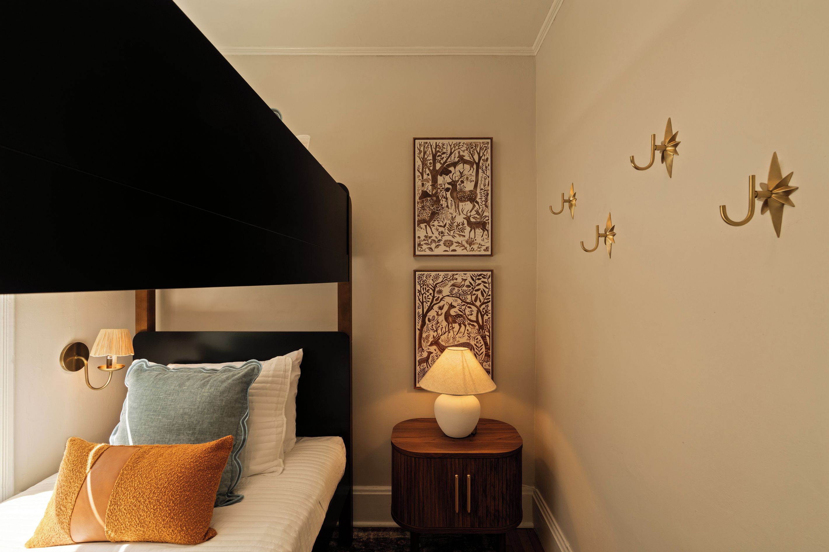 Un dormitorio con cama, almohadas, lámpara de noche, mesita de noche y decoración en la pared.
