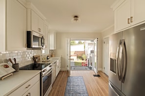 A kitchen with white cabinets, a stainless steel refrigerator, and a microwave.