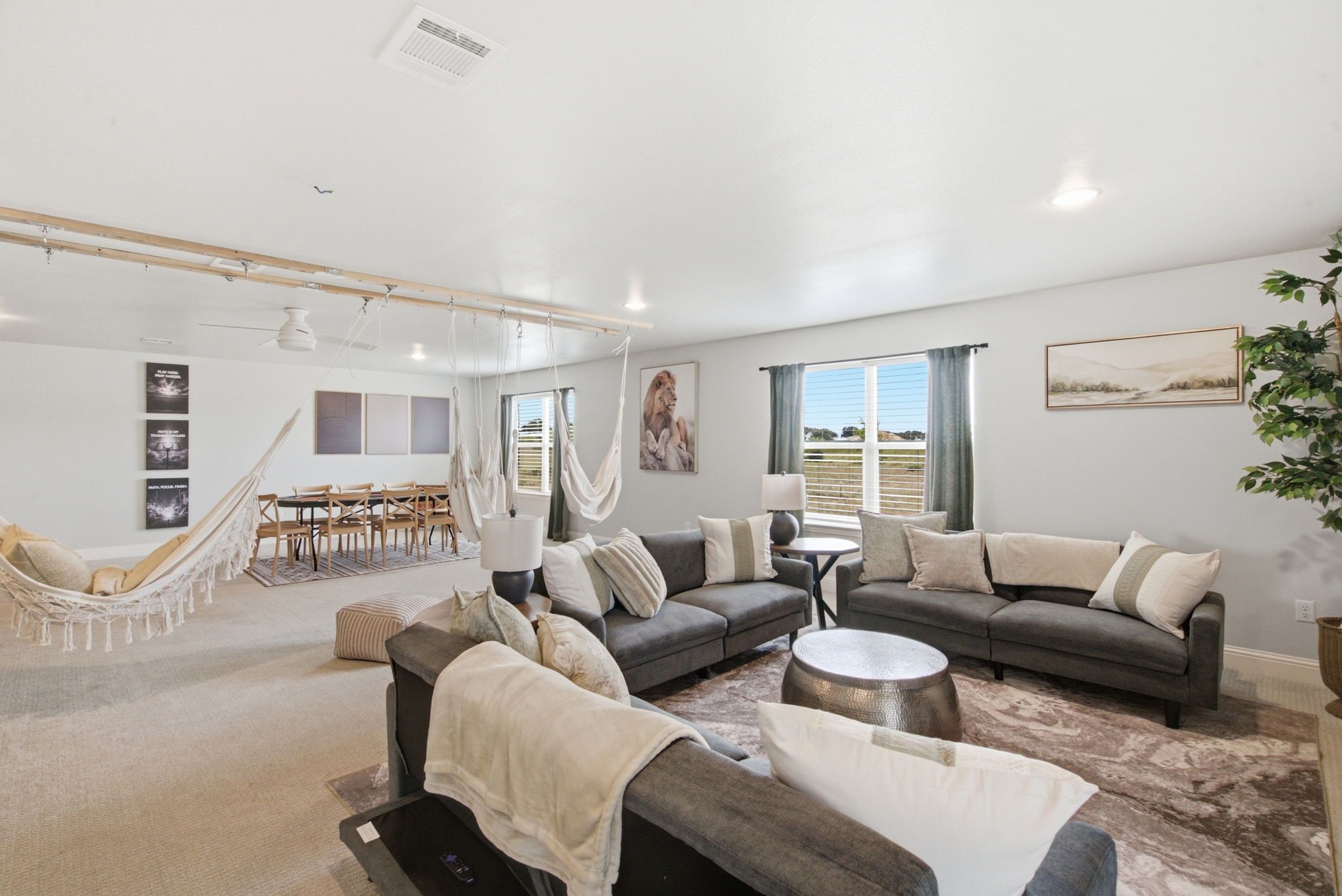 A spacious living area with a large sofa, a dining table, and a hammock.