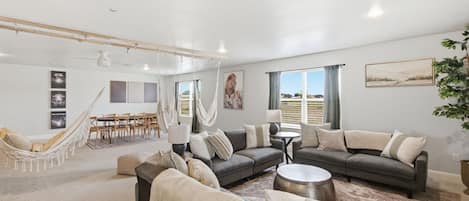 A spacious living area with a large sofa, a dining table, and a hammock.