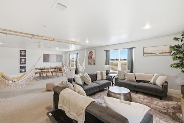 A spacious living area with a large sofa, a dining table, and a hammock.