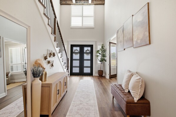 A spacious hallway with a wooden bench, a staircase, and a large door.
