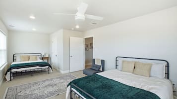 Ein Schlafzimmer mit zwei Betten, einem Deckenventilator und einer Tür zu einem anderen Raum.