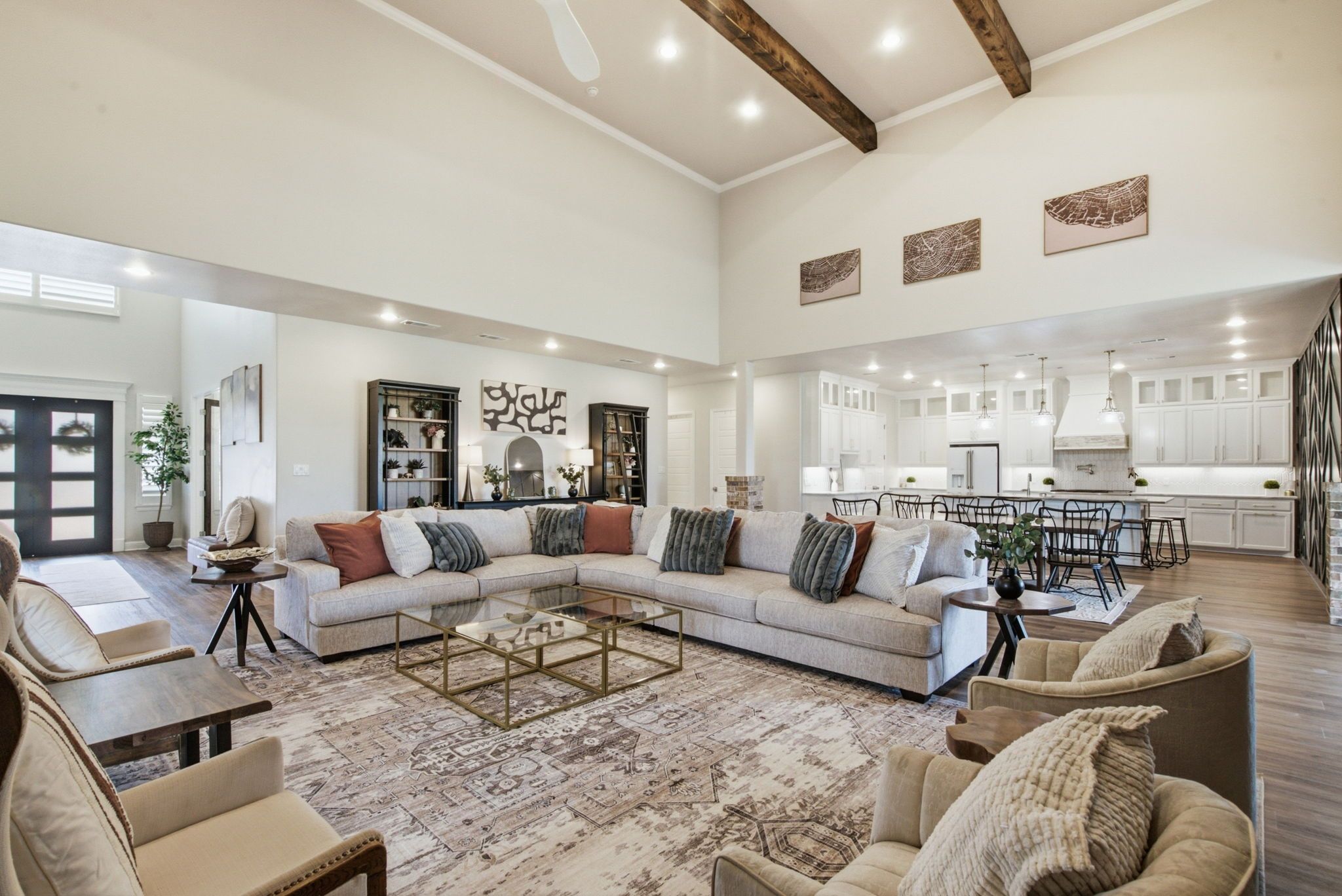 A spacious living area with a large sectional sofa, a coffee table, and a dining area with chairs and a kitchen in the background.
