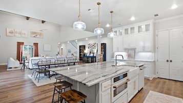 A spacious kitchen with a large island, white cabinetry, and pendant lighting.