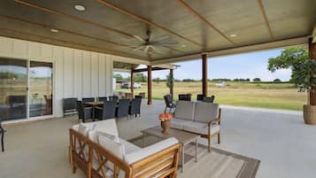 An outdoor covered patio with seating, a ceiling fan, and a view of the countryside.