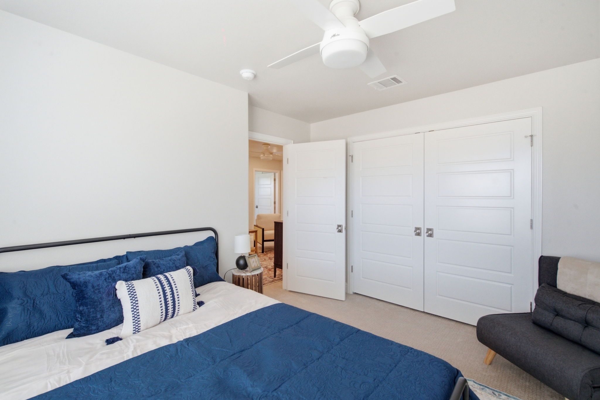 A bedroom with a bed, a ceiling fan, and a wardrobe.