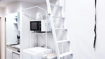 Una cocina compacta con microondas, cafetera y un refrigerador blanco.