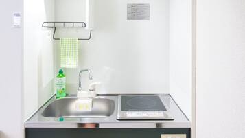 A bathroom with a sink, a mirror, a towel rack, and a bottle of liquid soap.