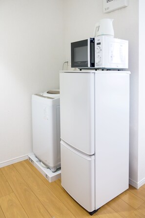 A white refrigerator with a microwave on top, a smaller white appliance below, and a wooden floor. - Triphome Tateishi Free WiFi Asakusa SkyTree (Katsushika City)