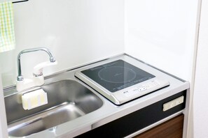 A kitchen with a built-in induction cooktop, a stainless steel sink, and a white countertop. - Triphome Tateishi Free WiFi Asakusa SkyTree (Katsushika City)