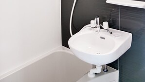 Ein modernes Badezimmer mit einer weißen Badewanne, einem weißen Waschbecken und einer schwarzen Wand.