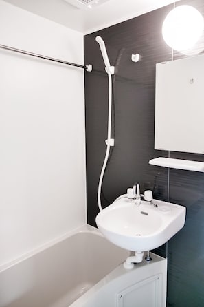 A modern bathroom with a white bathtub, a white sink, and a black wall. - Triphome Tateishi near Asakusa Skytree (Katsushika City)