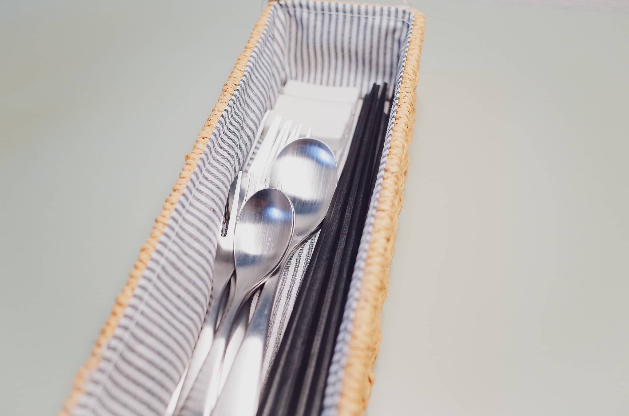 Un panier tressé contenant une cuillère et une fourchette.