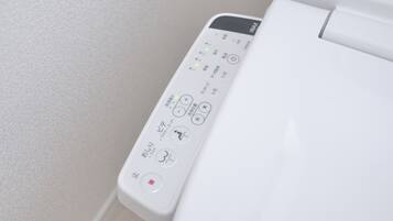 A toilet with a control panel featuring various buttons and symbols, including a red light indicator.