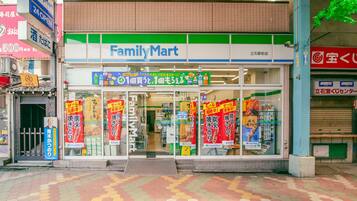 Una tienda FamilyMart con entrada de baldosas, ventanas de vidrio y pancartas promocionales.