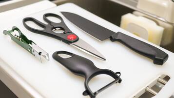A kitchen drawer with various utensils including scissors, a knife, and a can opener.