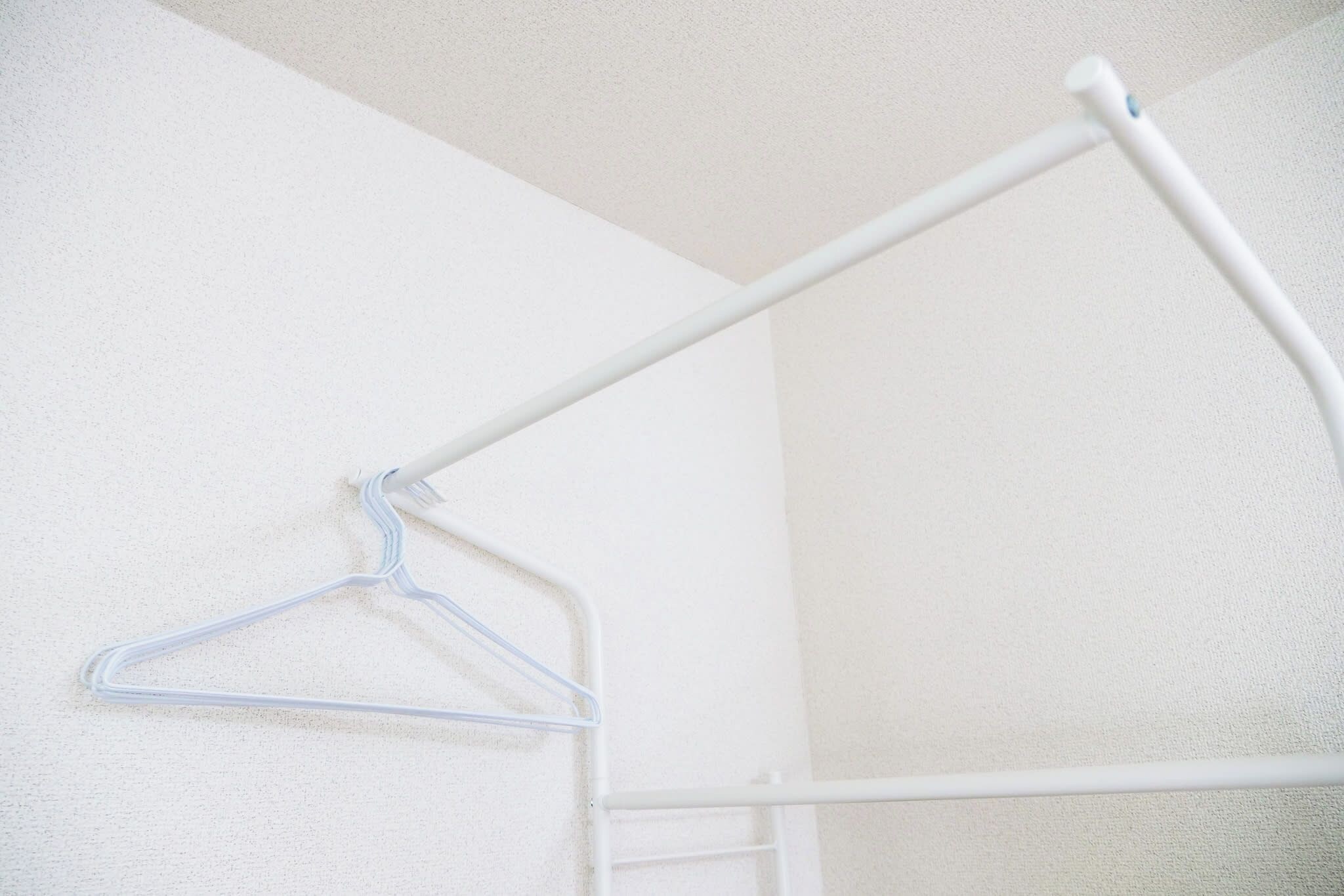 Eine weiße Wand mit einem Metallhaken und einem weißen Metallgestell.