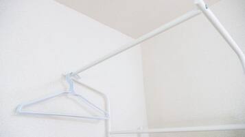 Eine weiße Wand mit einem Metallhaken und einem weißen Metallgestell.