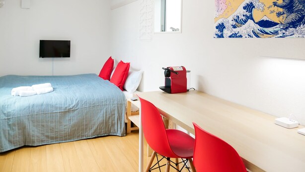 Ein Hotelzimmer mit Bett, Schreibtisch, Stuhl, Fernseher und einem Bild an der Wand.