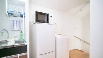 A compact kitchen with a refrigerator, microwave, sink, and a small countertop.